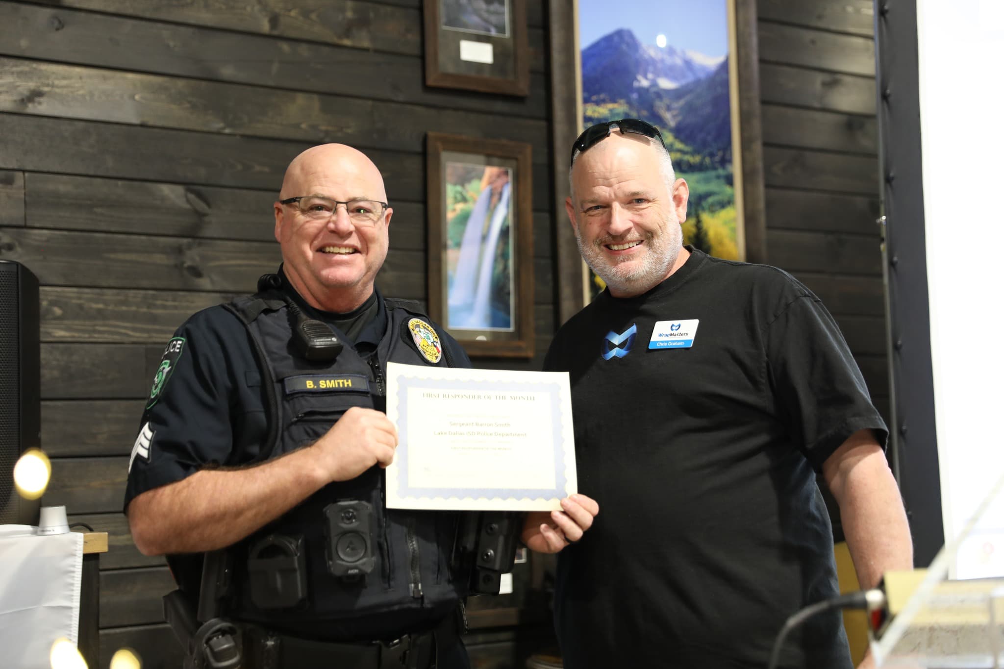 Chris Graham presenting a First Responder of the Month certificate to a Lake Dallas ISD police sergeant