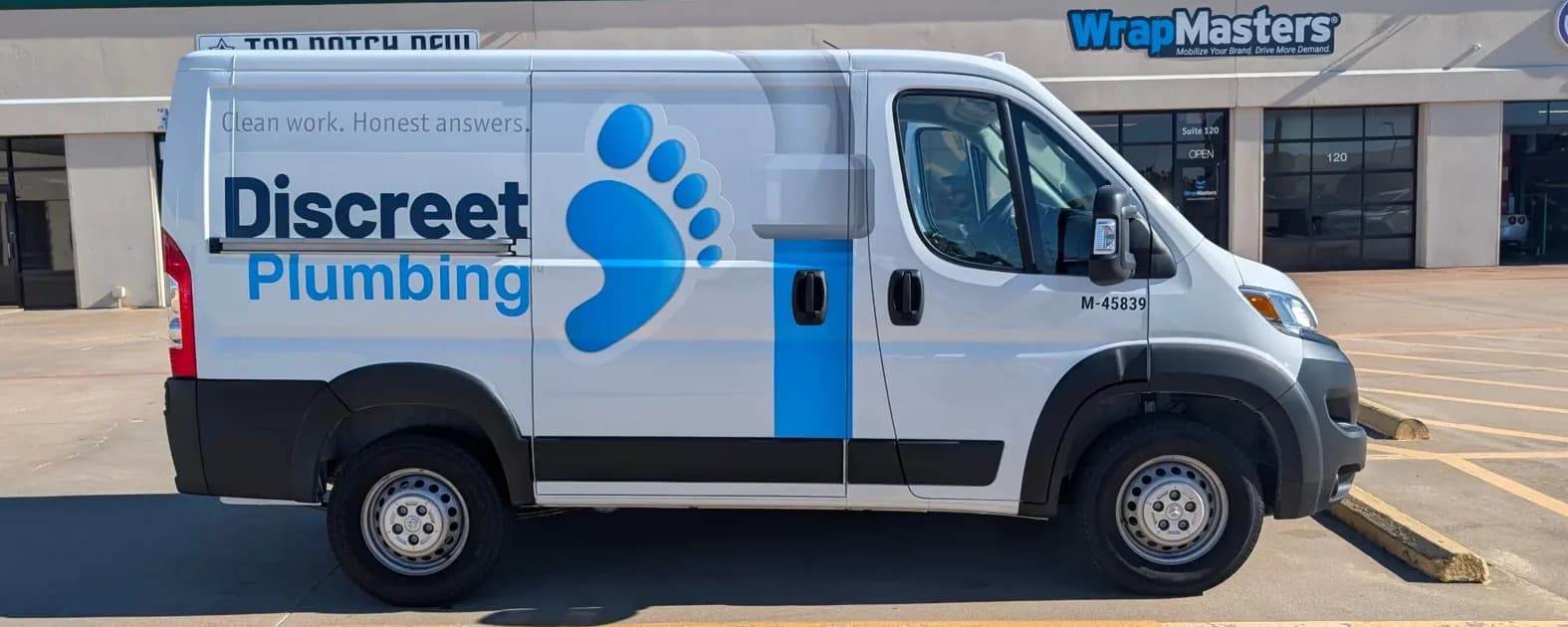 Discreet Plumbing Ram ProMaster van with a partial wrap: the name, a blue footprint mark, and the line Clean work. Honest answers.
