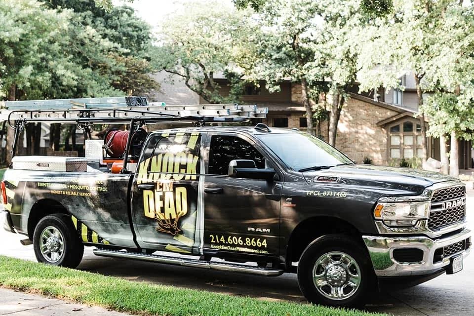 Knock Em Dead Pest Control's earlier truck: a dark wrap on a dark truck, with the company name split across the window line