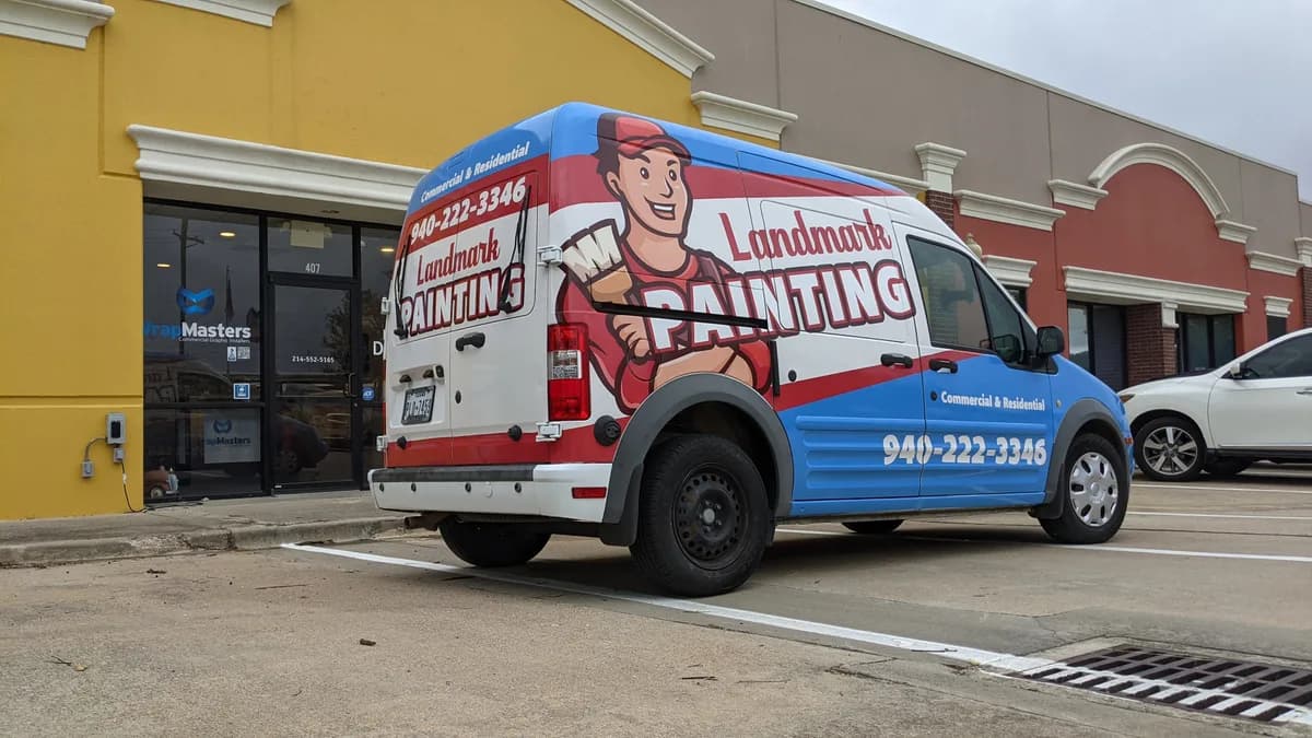 Landmark Painting van fully wrapped in red, white, and blue with a painter mascot and phone number