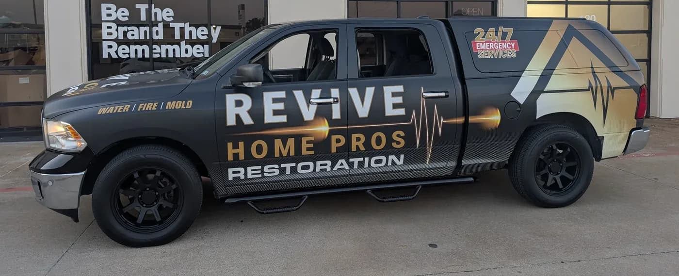 The same Revive Home Pros pickup after its WrapMasters wrap, parked outside the WrapMasters shop in Denton