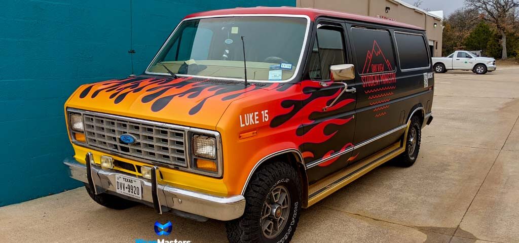 Classic Ford van with a fiery orange and black custom wrap by WrapMasters, featuring "PARKER VAN" branding, parked in front of a teal wall.